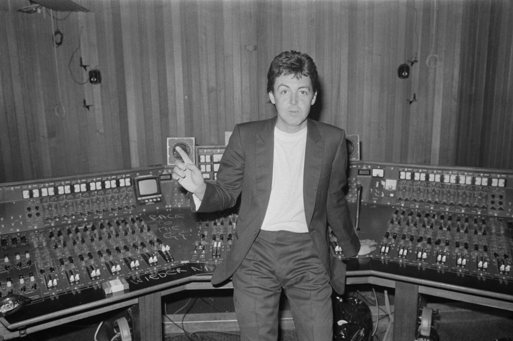 Paul McCartney standing against a mixing console at Abbey road Studios.